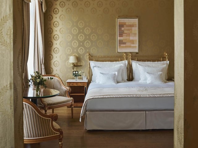 Hotelzimmer mit Messingbett und goldener Tapete