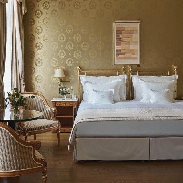 Hotelzimmer mit Messingbett und goldener Tapete