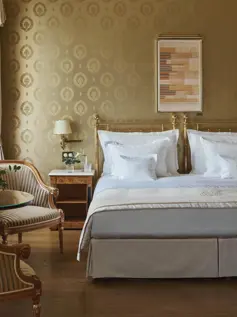 Hotelzimmer mit Messingbett und goldener Tapete