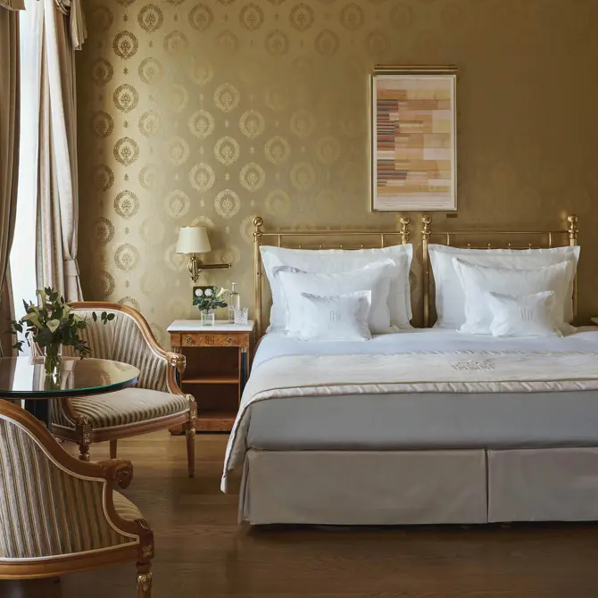 Hotelzimmer mit Messingbett und goldener Tapete