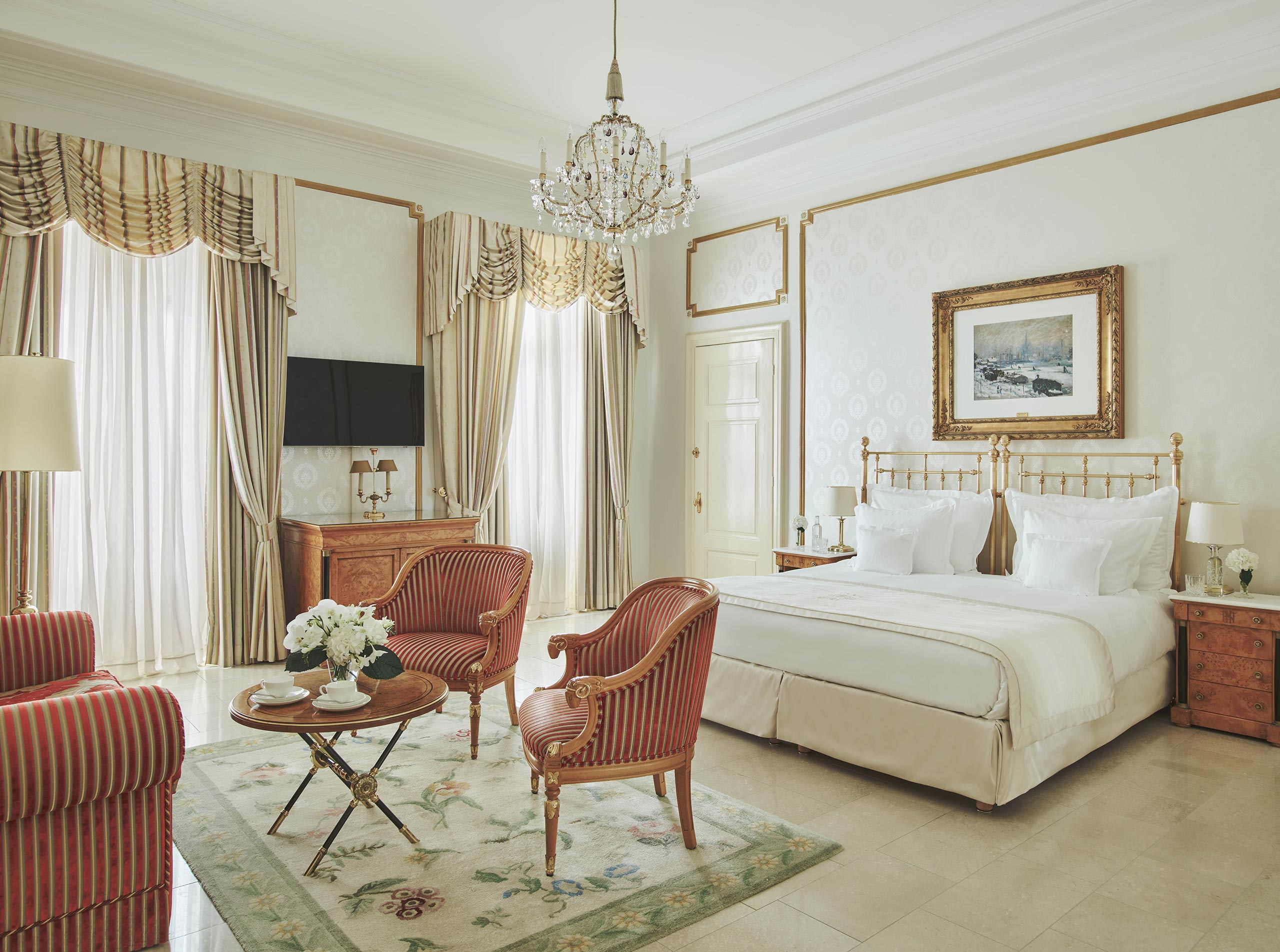 Junior Suite mit Messingbett, hohen Fenstern und Polstergruppe